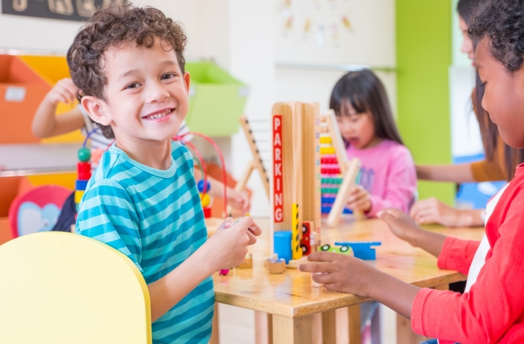 stock-photo-kindergarten-students-smile-when-playing-toy-in-playroom-at-preschool-international-education-698288386