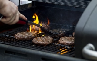 A man grilling burgers on a grille outside